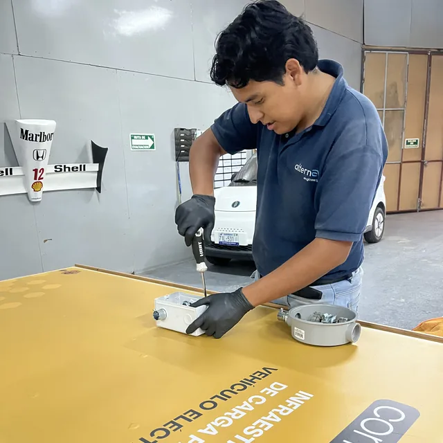 Integrante de AlternEV montando componentes sobre un panel de demostración de infraestructura de carga