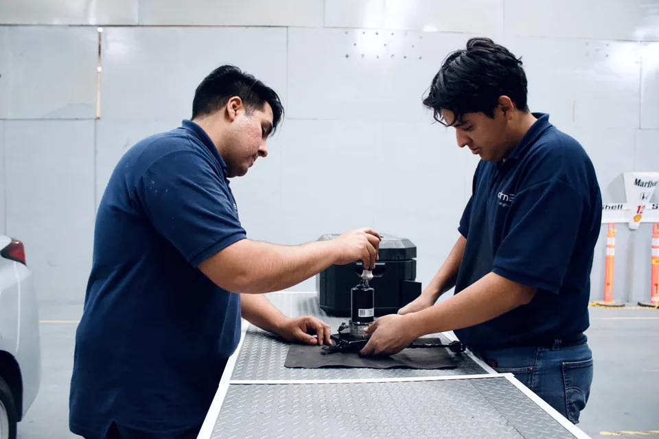 Dos técnicos de AlternEV trabajan sobre un componente en una mesa del taller